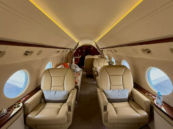 Beige club seats beside the oval windows of a private jet cabin
